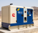 Diesel generator in a soundproof canopy at a sun-baked, high-altitude industrial site in Pakistan, where heat and thin air cut output